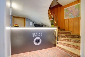 Un mostrador de recepción de hotel con un letrero que dice "CENTRO HOTELS" y una escalera que lleva a un interior de madera.