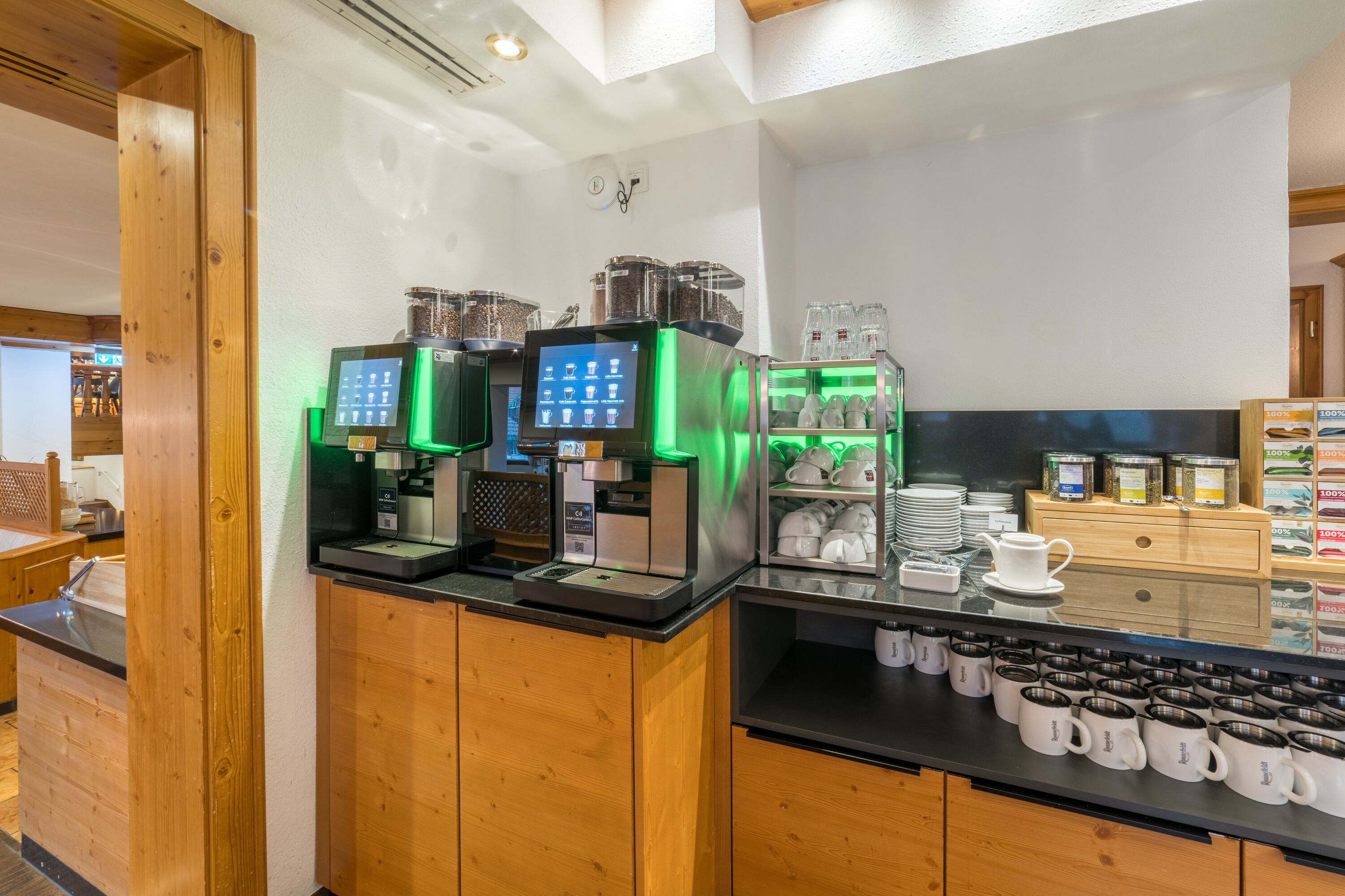 A coffee station with multiple coffee machines and a display of mugs.