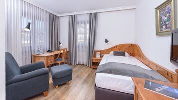 A hotel room with a bed, a desk, a chair, and a TV.