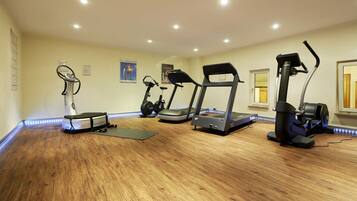 A home gym with a treadmill, elliptical, and stationary bike.