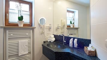 Un baño moderno con encimera negra, un perchero, un espejo y una planta en maceta.