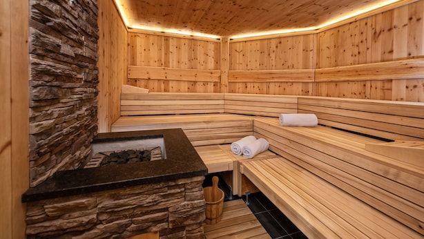 Una sauna con bancos de madera y pared de piedra.