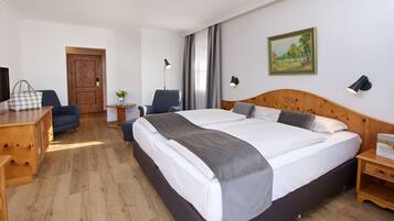 A hotel room with a large bed, a desk, a chair, a lamp, and a painting on the wall.