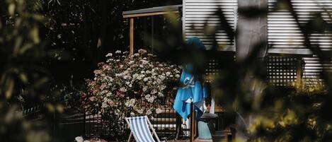 A swimming pool with a blue fence, a chair, and a covered area with a table and umbrella.