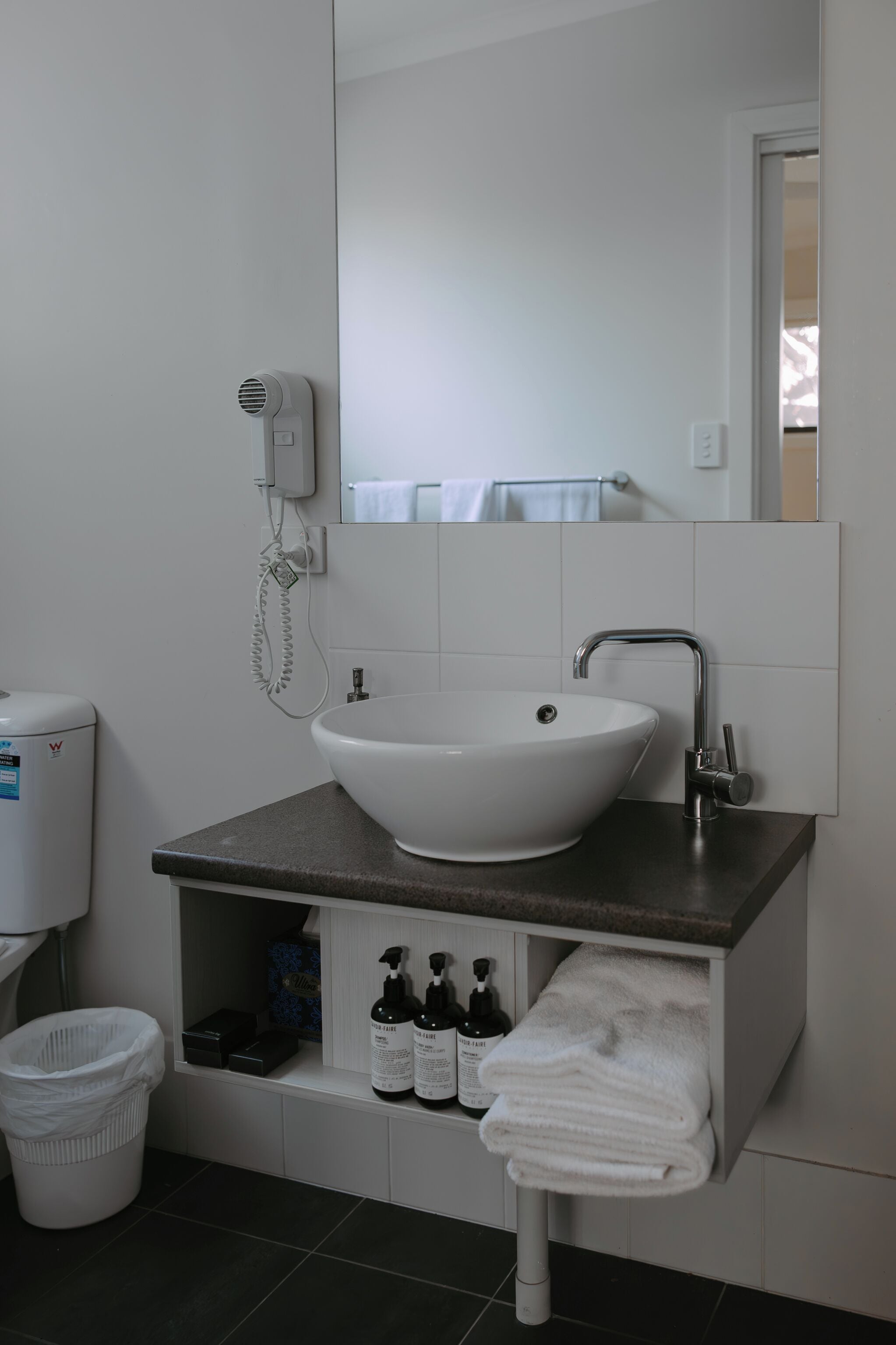 A bathroom with a white sink, a mirror, a towel rack, and a hairdryer.
