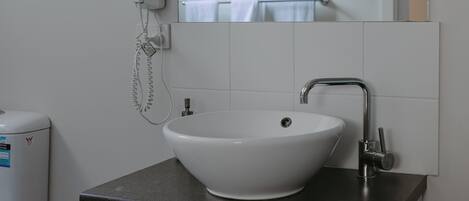A bathroom with a white sink, a mirror, a towel rack, and a hairdryer.