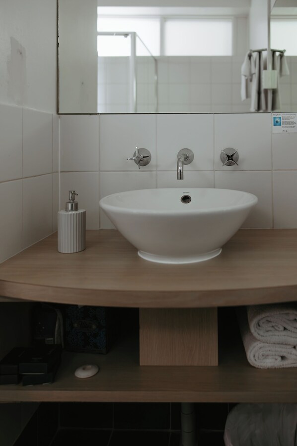 Une salle de bain avec un lavabo blanc, deux robinets et un distributeur de savon.