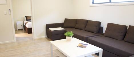 A modern living room with a brown sectional sofa, a white coffee table, and a small potted plant.