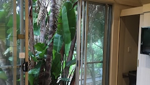 A room with a sliding glass door leading to a balcony with large green plants. - Seafront Hotel Kangaroo Island (Penneshaw)