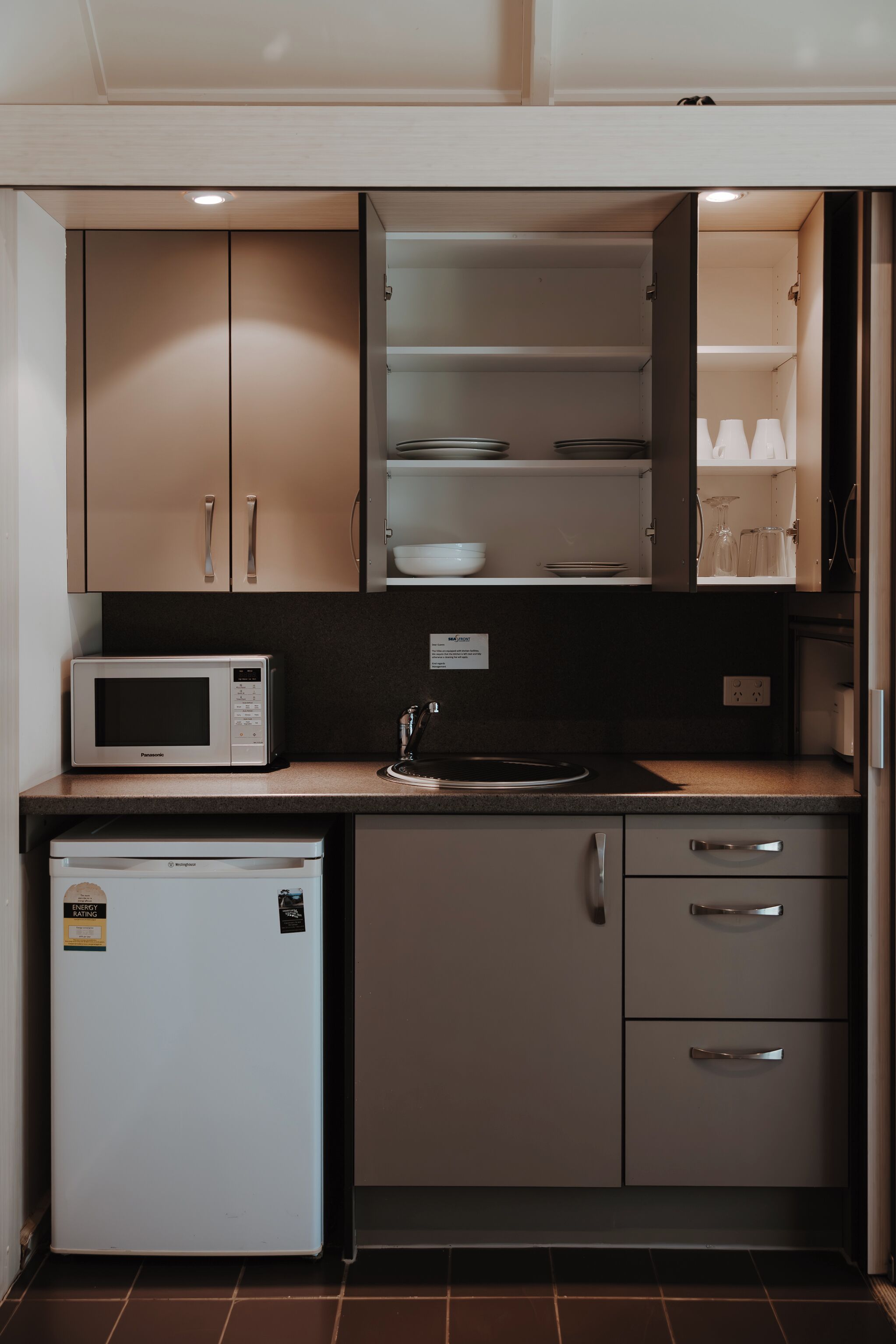 A compact kitchen with a microwave, refrigerator, and cabinets.