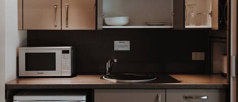 A compact kitchen with a microwave, refrigerator, and cabinets.
