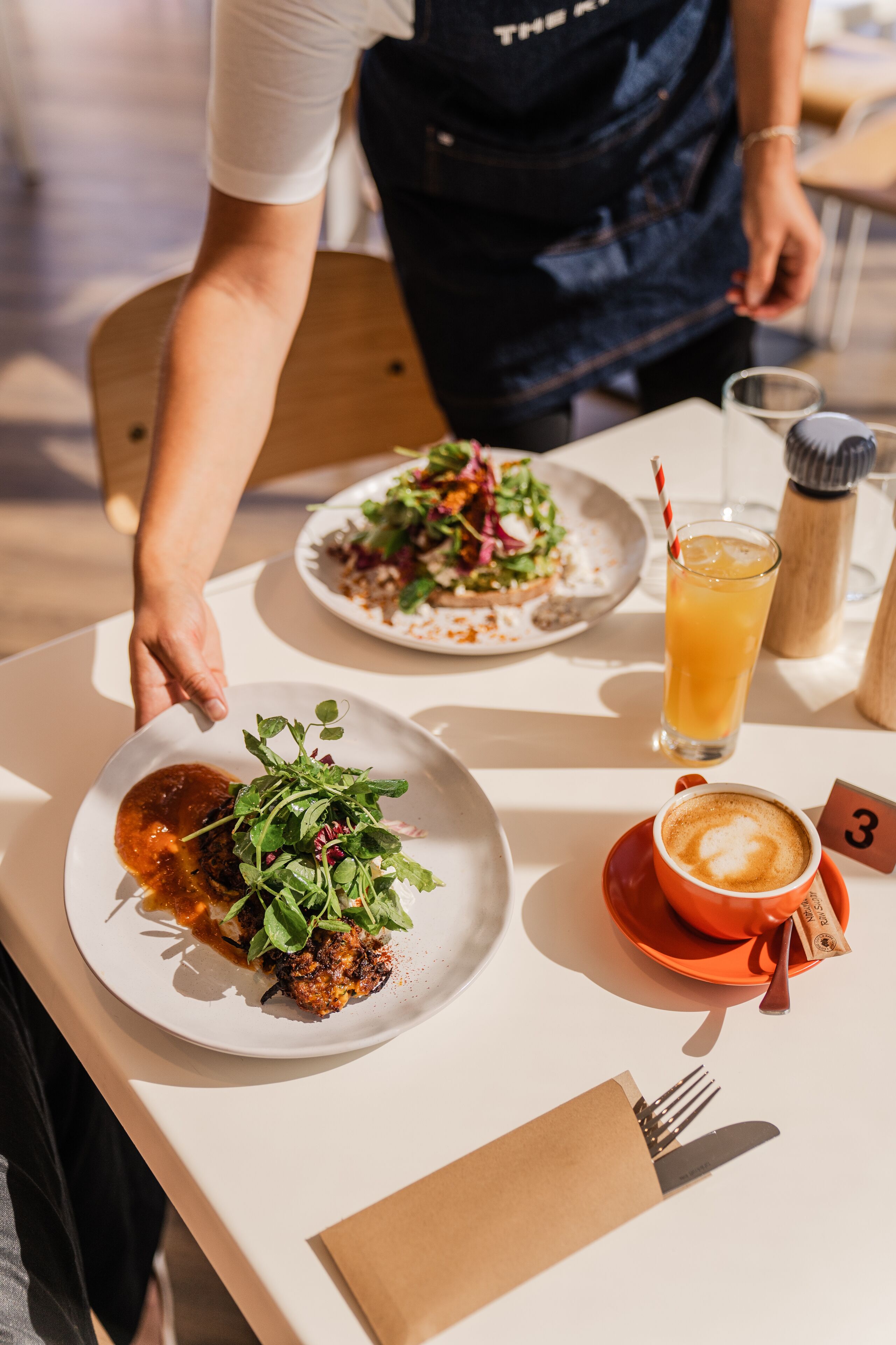A dining table with plates of food, a glass of orange juice, and a cup of coffee.