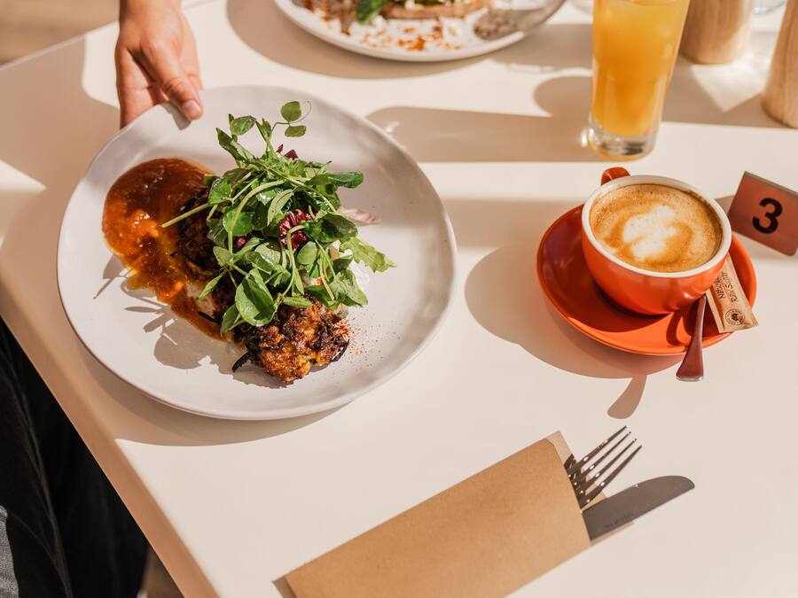 Een eettafel met borden eten, een glas sinaasappelsap en een kop koffie.