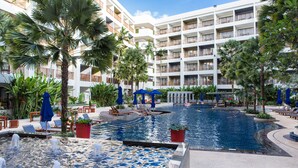 A hotel pool area with multiple levels, palm trees, and lounge chairs. - Deevana Plaza Phuket (Patong)