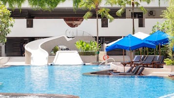 Relax by the pool surrounded by lush greenery and palm trees.