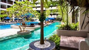 A hotel pool area with a circular water feature, lounge chairs, and umbrellas. - Deevana Plaza Phuket (Patong)