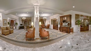 A spacious lobby with high ceilings, marble flooring, and elegant furniture.