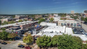 An aerial view of a cityscape with various buildings, parking lots, and streets.