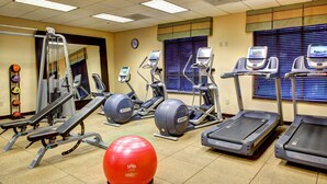 A gym with treadmills, elliptical machines, and a red exercise ball.