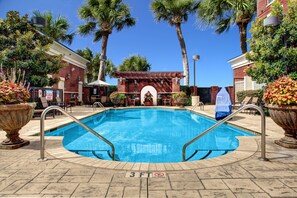 A swimming pool with a 3 FT no diving sign, surrounded by palm trees and a brick building. - Hilton Columbia Center (Columbia)