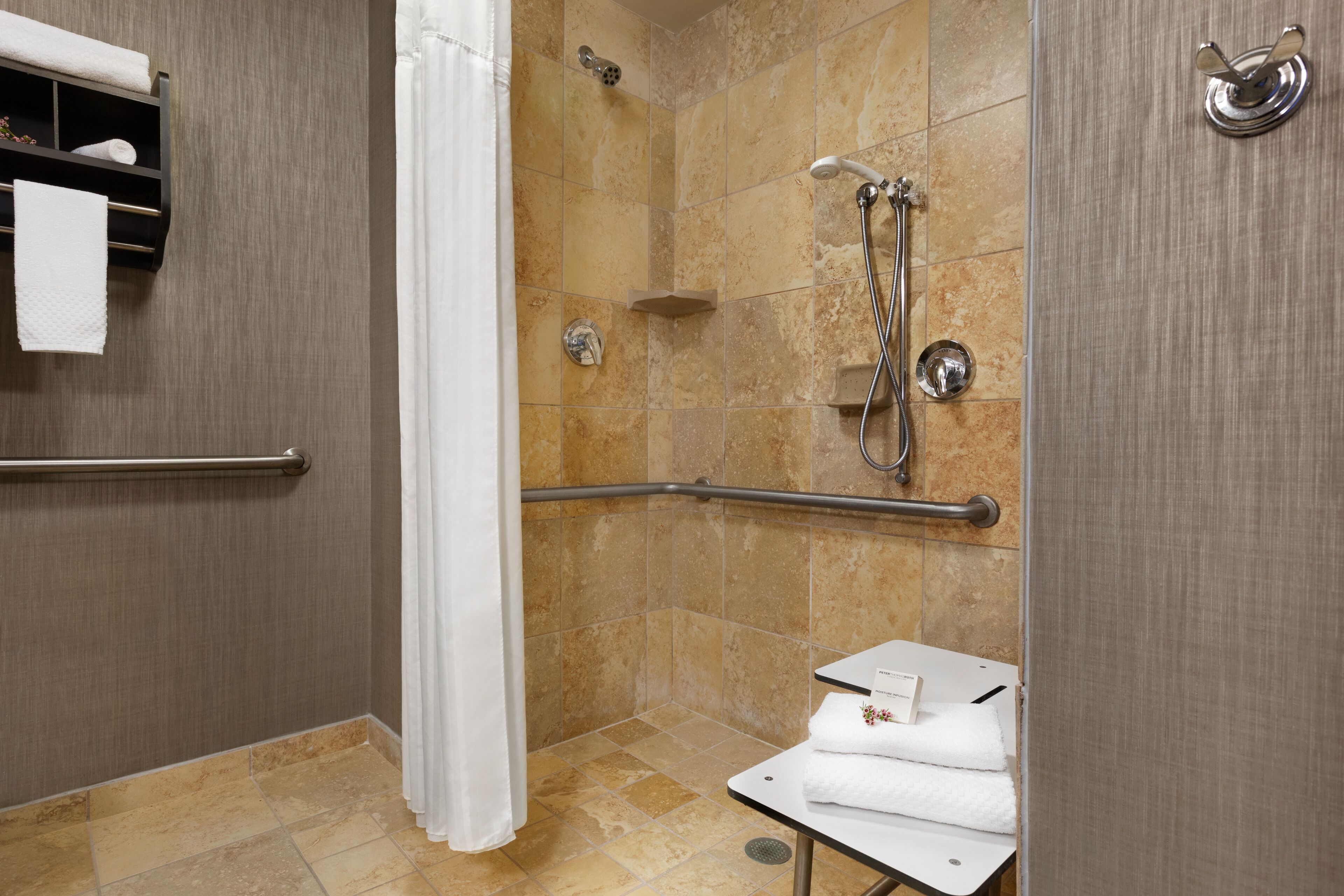 A shower area with a grab bar, a towel rack, and a small table with towels.