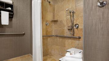 A shower area with a grab bar, a towel rack, and a small table with towels.