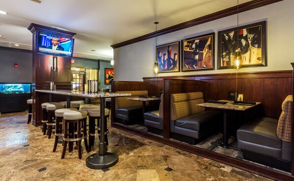 A bar area with seating, a television screen, and framed artwork on the wall.