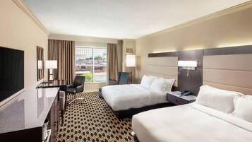 A hotel room with two beds, a desk, a chair, a TV, and a window with curtains.