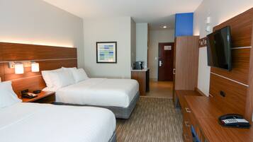 A hotel room with two beds, a desk with a telephone, a television, and a framed picture on the wall.