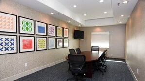 A conference room with a long table, chairs, a flat-screen TV, and framed artwork on the wall. - Holiday Inn Express & Suites New Boston by IHG (New Boston)