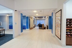 A hotel corridor with a reception desk, seating area, and a snack bar.
