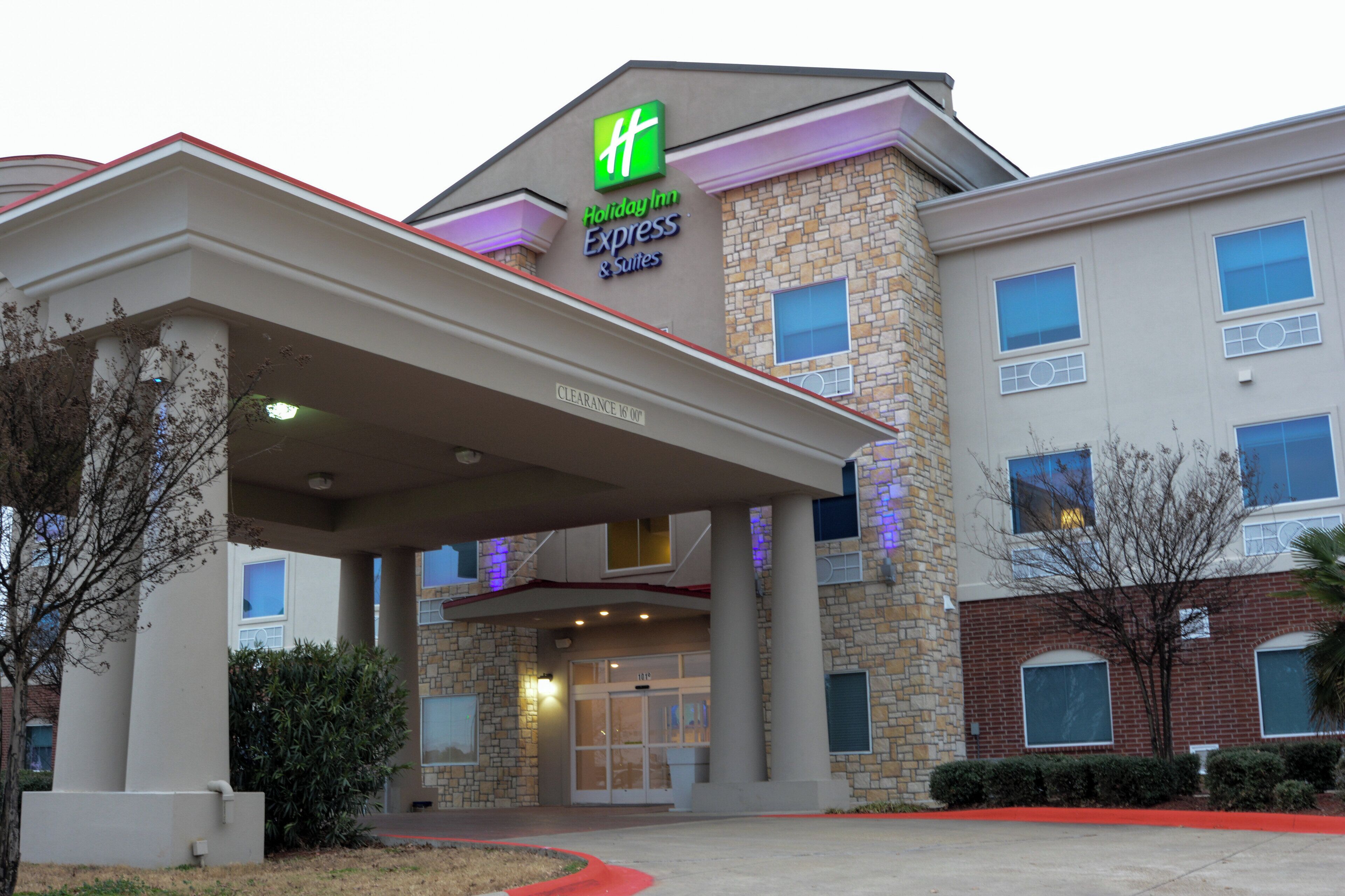 A Holiday Inn Express & Suites building with a stone facade, a covered entrance, and a clear sign indicating the name and services.