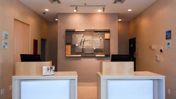 Un espace d’accueil au design moderne, comprenant un comptoir de réception, un panneau mural et un plafond doté d’un éclairage encastré.