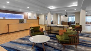 Un hall d’entrée spacieux avec un comptoir de réception, des coins salon confortables et un espace dédié aux repas.