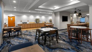 Un hall d'hôtel moderne avec un comptoir d'accueil, un espace salon et une cuisine en arrière-plan.