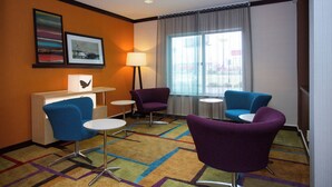 A hotel room with a desk, two purple armchairs, a small table, and a window with curtains. - Fairfield Inn & Suites by Marriott Cordele (Cordele)