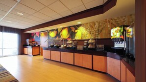 A hotel reception area with a counter displaying various food items and a large fruit mural on the wall. - Fairfield Inn & Suites by Marriott Cordele (Cordele)