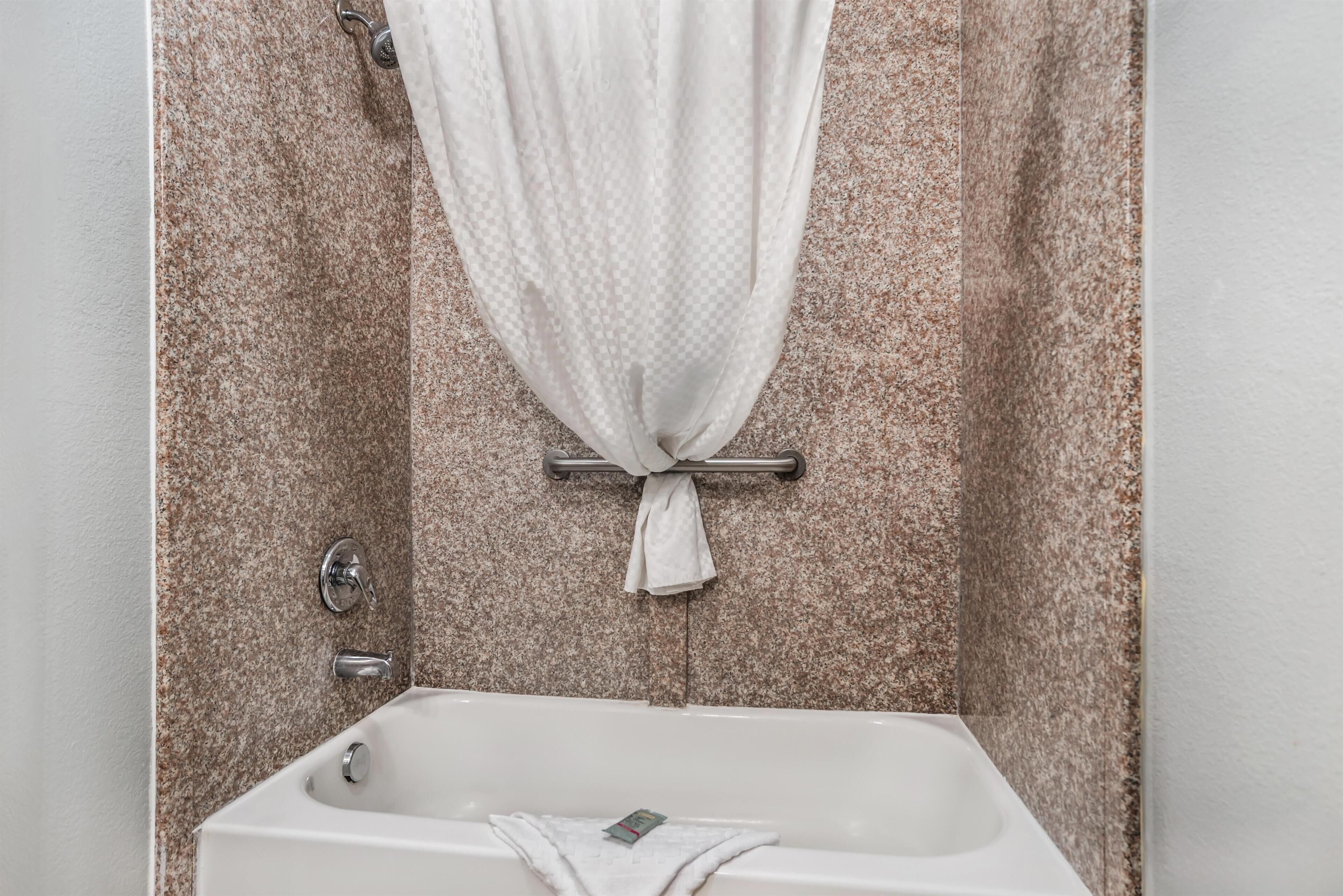 Un baño con bañera, toallero y cortina de ducha.