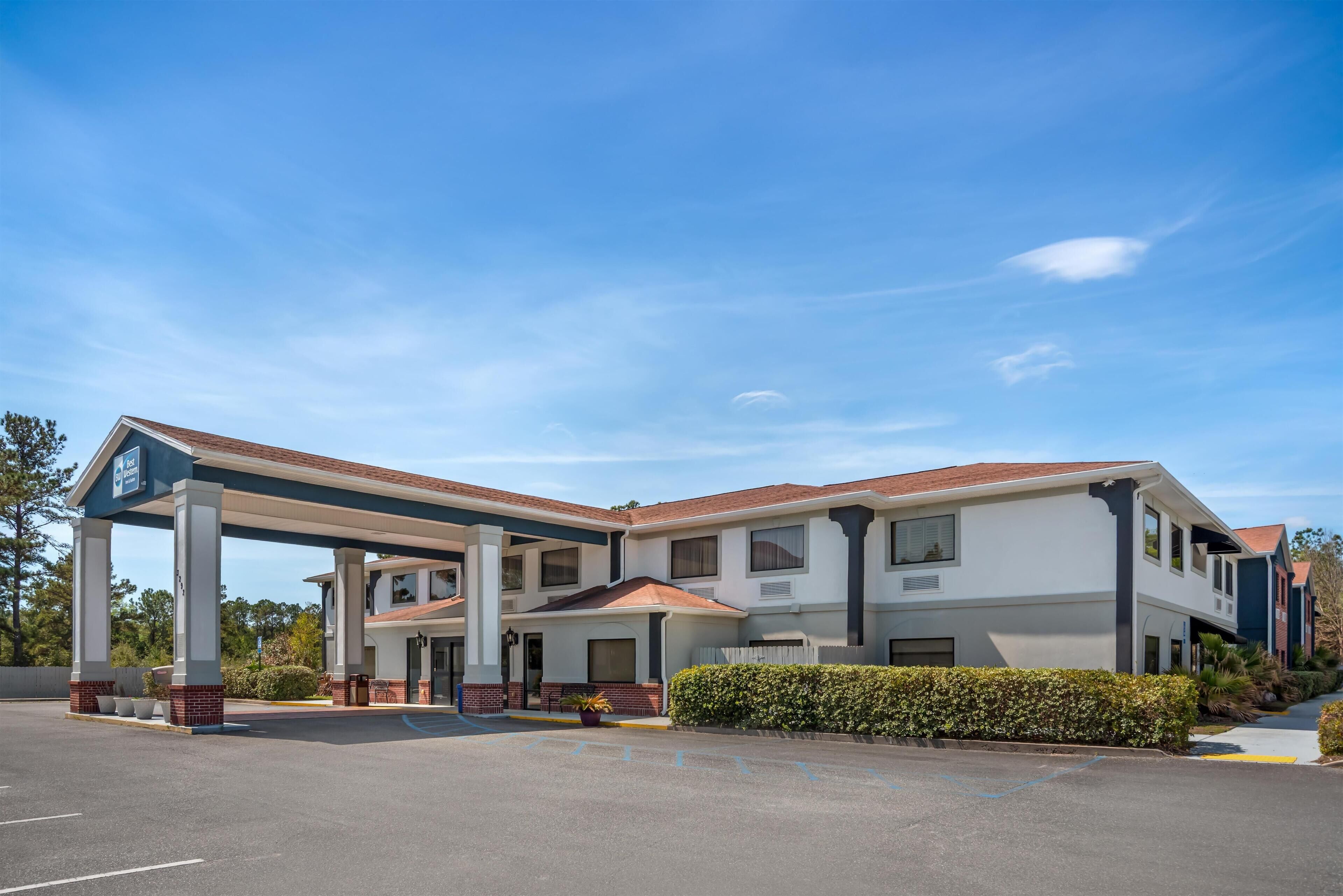Ein Motel mit Tankstelle, mehreren Zimmern und einem Parkplatz.