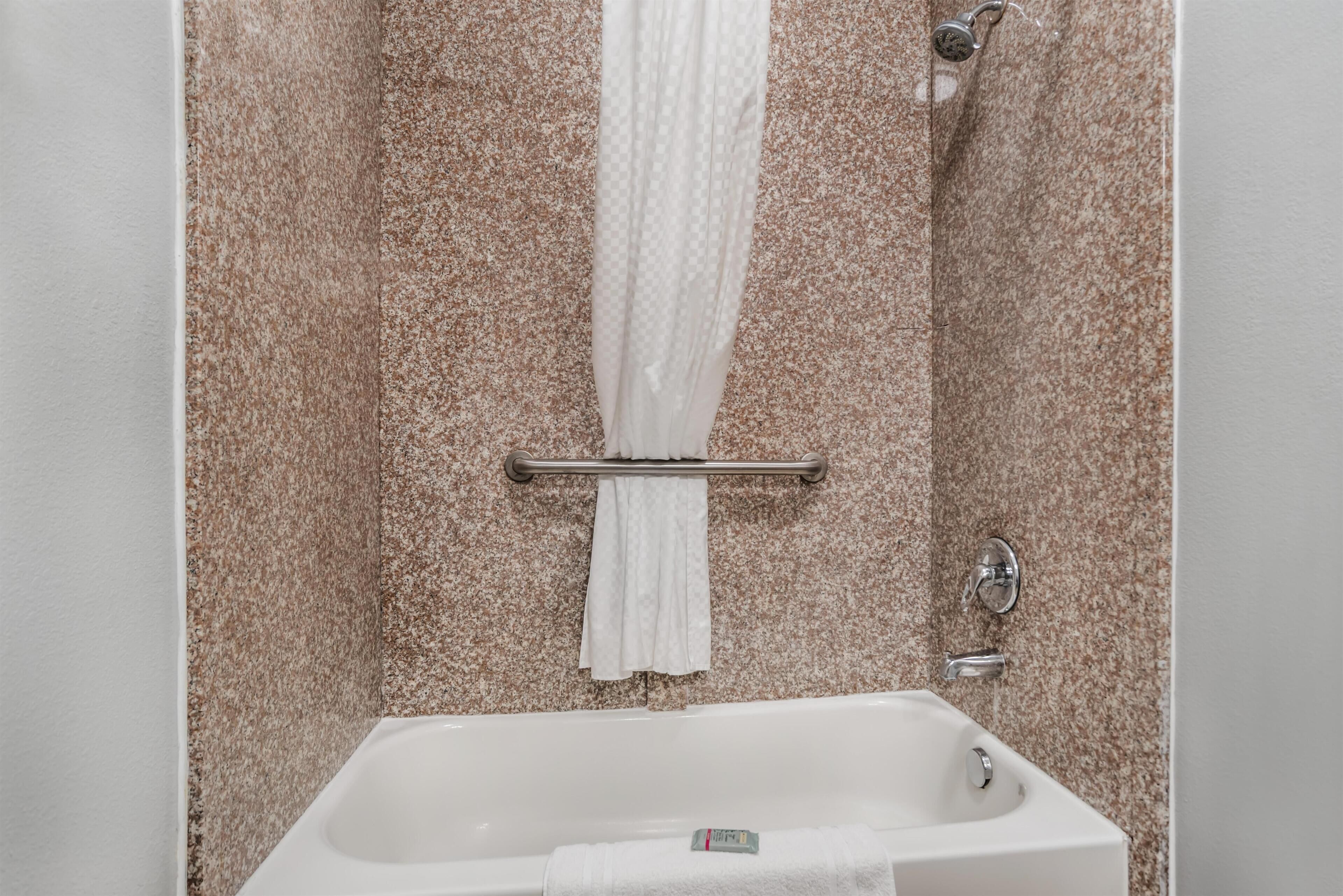 Un baño con bañera, perchero y cortina de ducha.