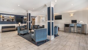 Eine moderne Hotelhalle mit einer Couch, Sesseln, einem Schreibtisch und einem Fernseher.