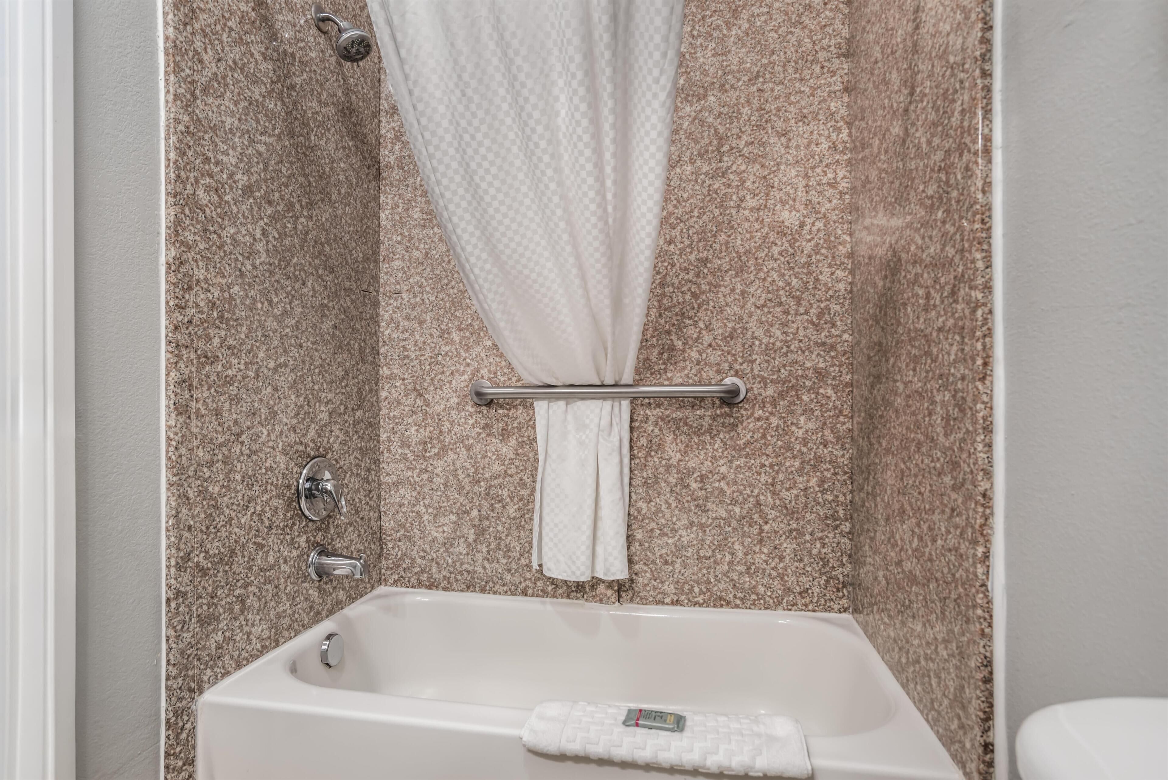 A bathroom with a bathtub, a shower curtain, a towel rack, and a toilet.
