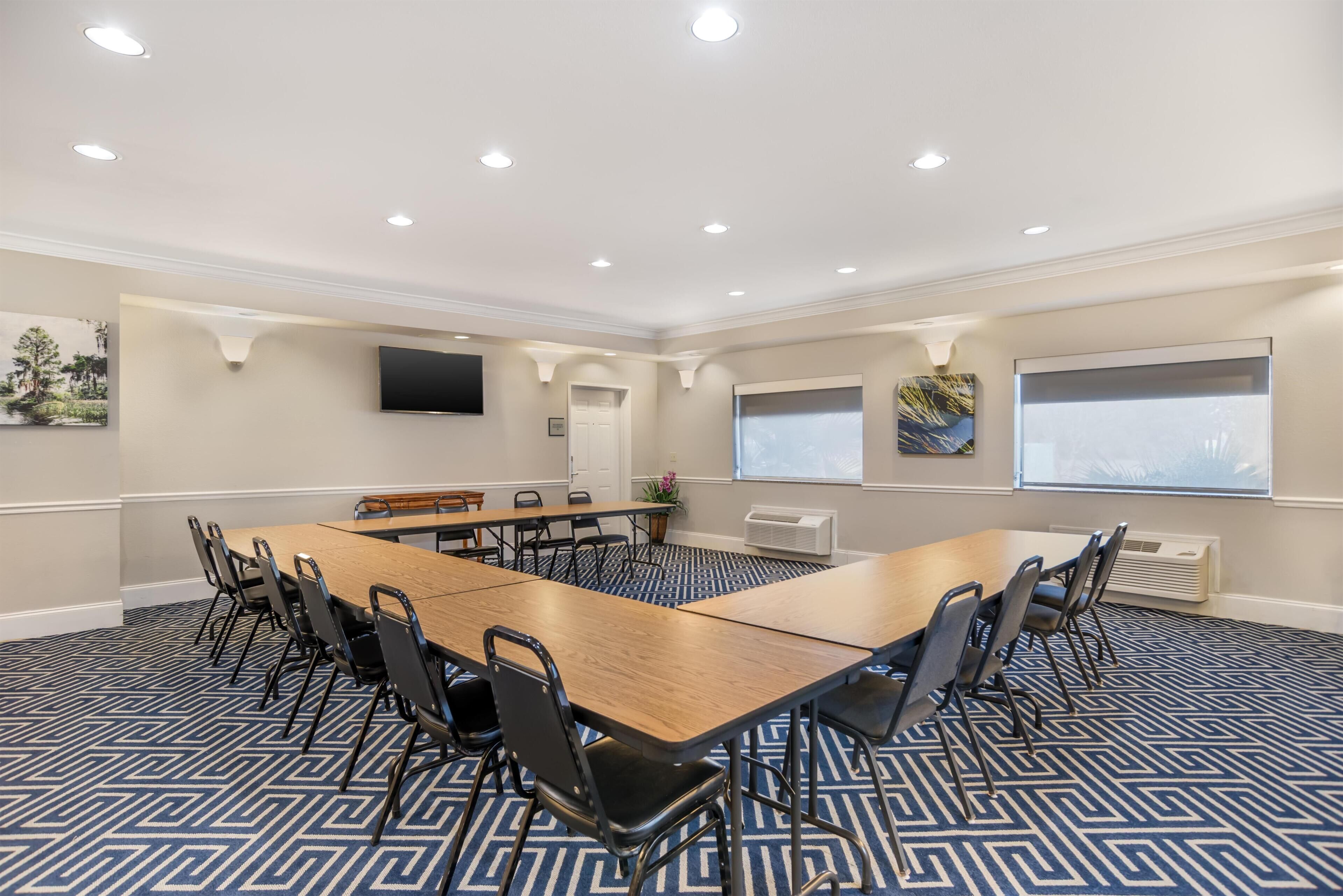 A conference room with a long table, chairs, a TV, and artwork on the walls.