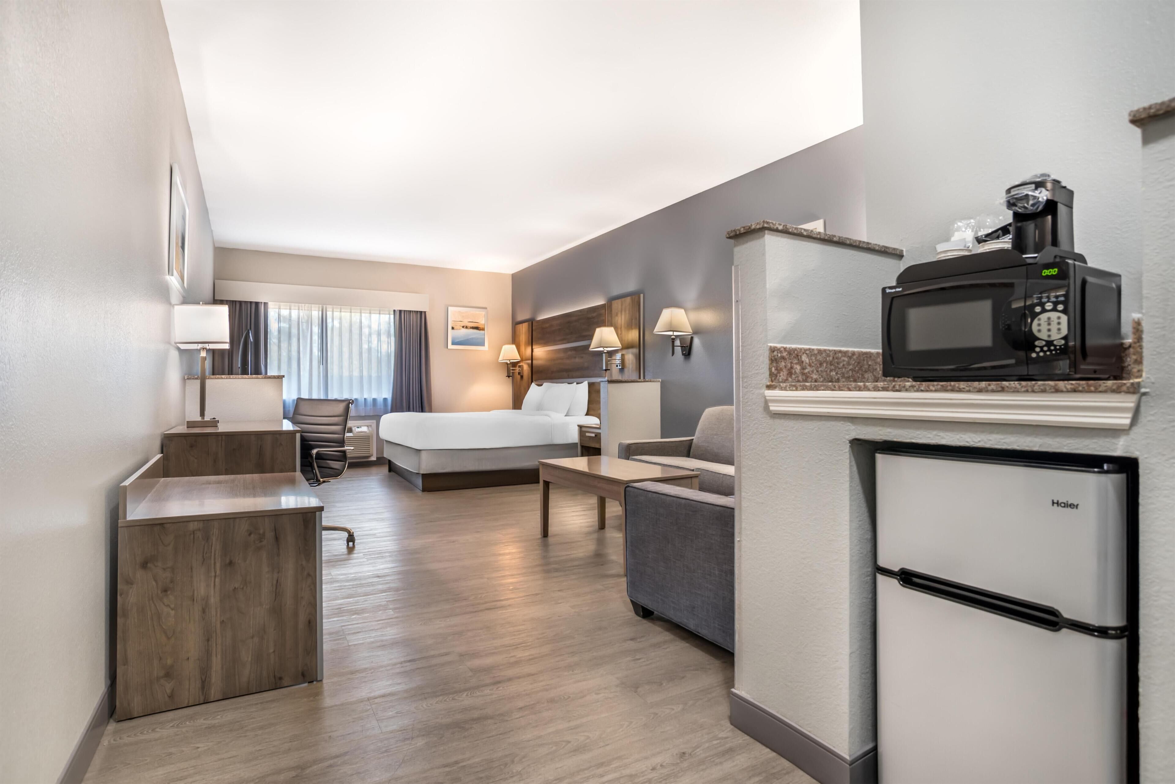 Une chambre d’hôtel équipée d’un lit, d’un bureau, d’une kitchenette et offrant une vue sur l’extérieur.