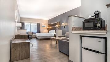 Une chambre d’hôtel équipée d’un lit, d’un bureau, d’une kitchenette et offrant une vue sur l’extérieur.