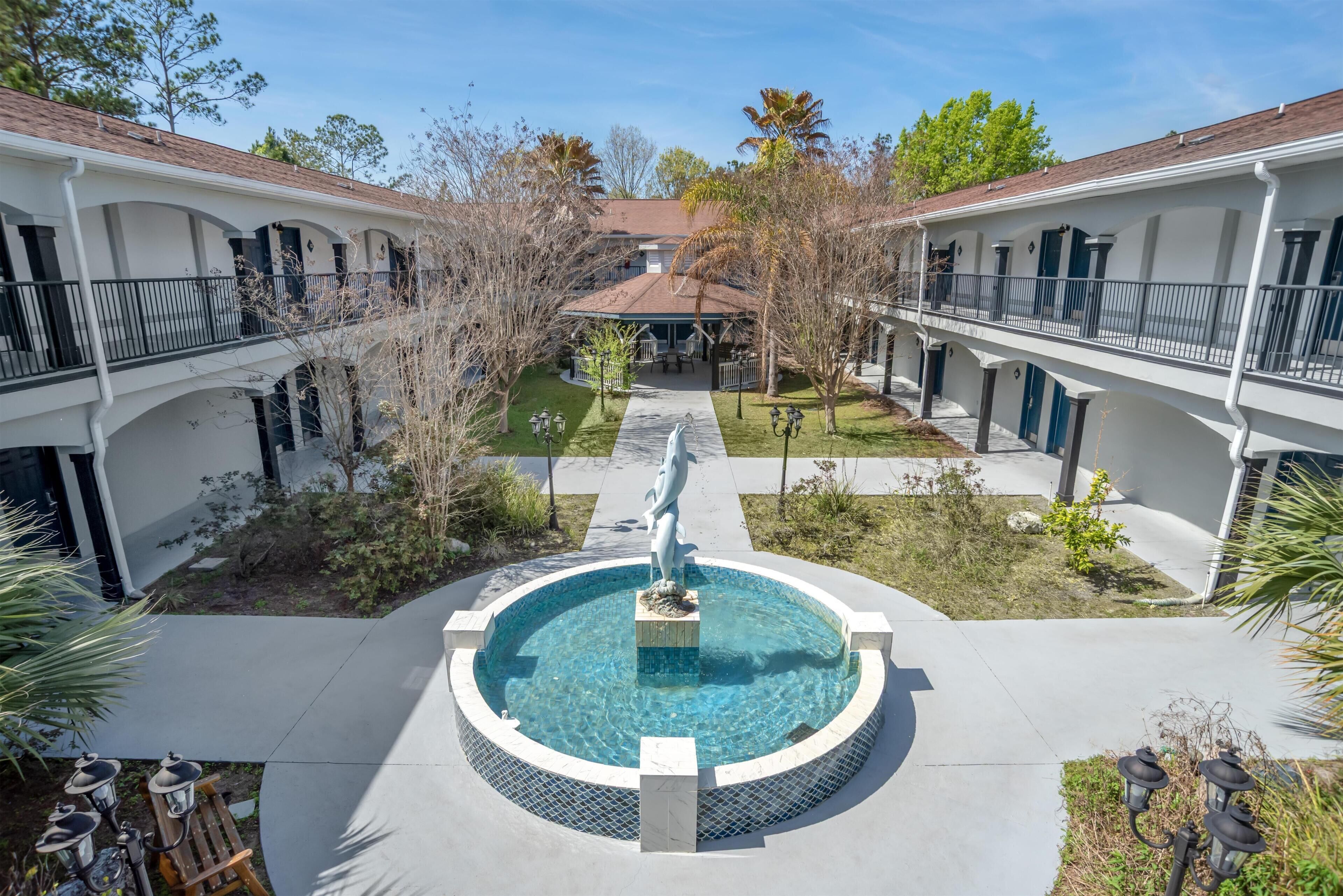 A courtyard with a central pool, a statue, and a building with balconies.