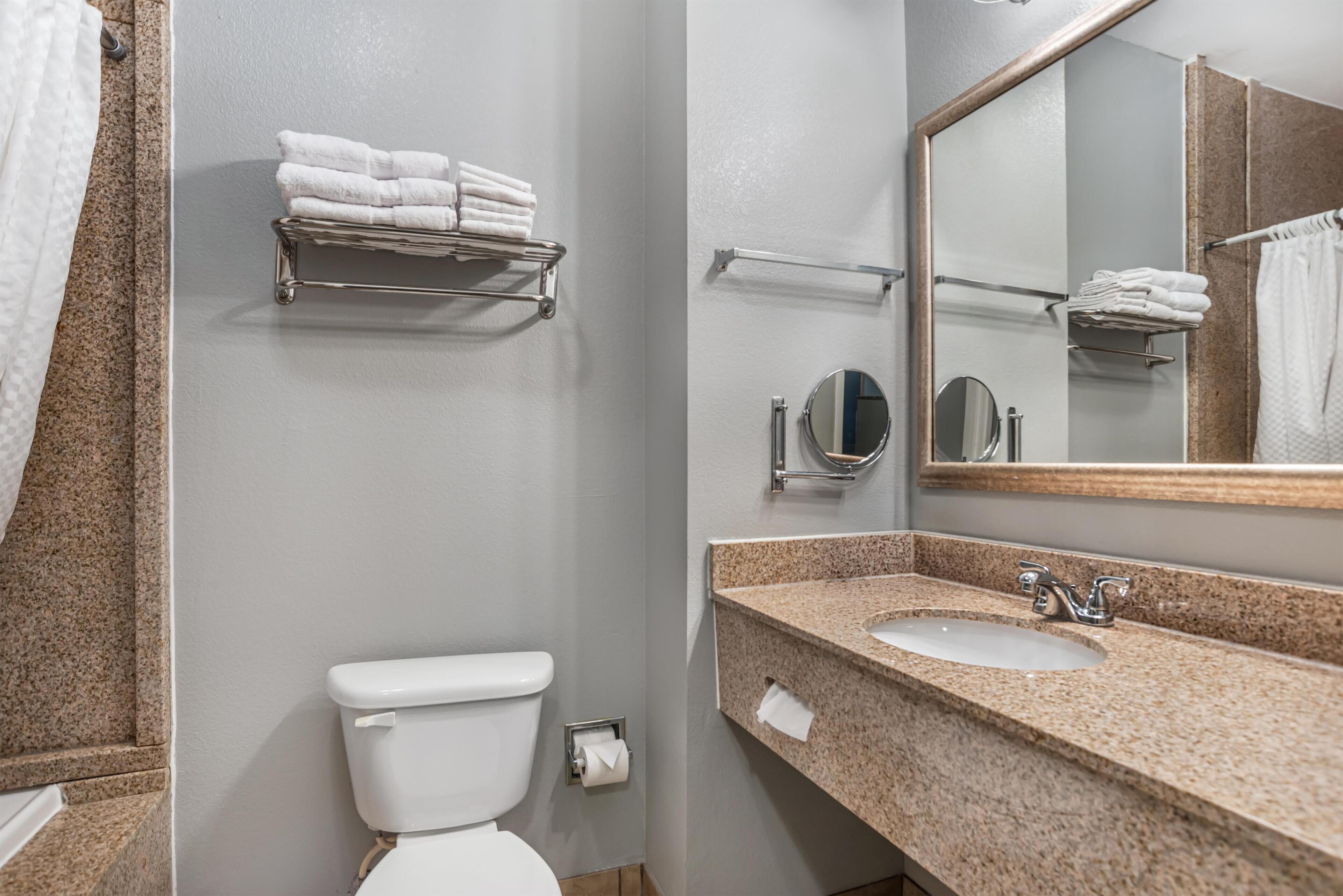 A bathroom with a toilet, sink, towel rack, and mirror.