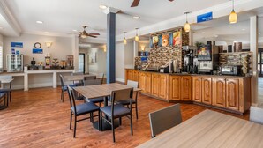 Eine Hotelhalle mit Kaffee-Bar, Sitzgelegenheiten und einer Uhr an der Wand.