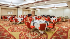 A conference room with round tables, red chairs, and a carpeted floor.