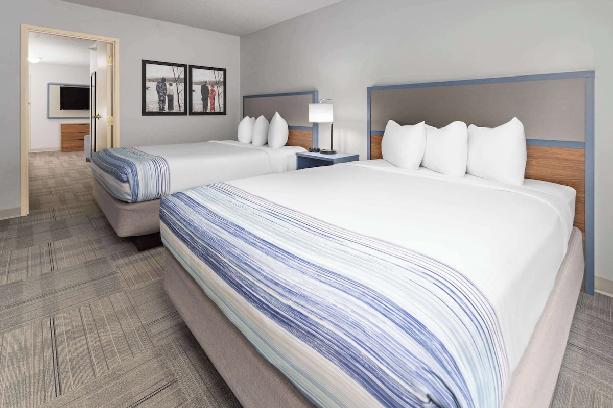 A hotel room with two beds, a TV, and a framed picture on the wall.